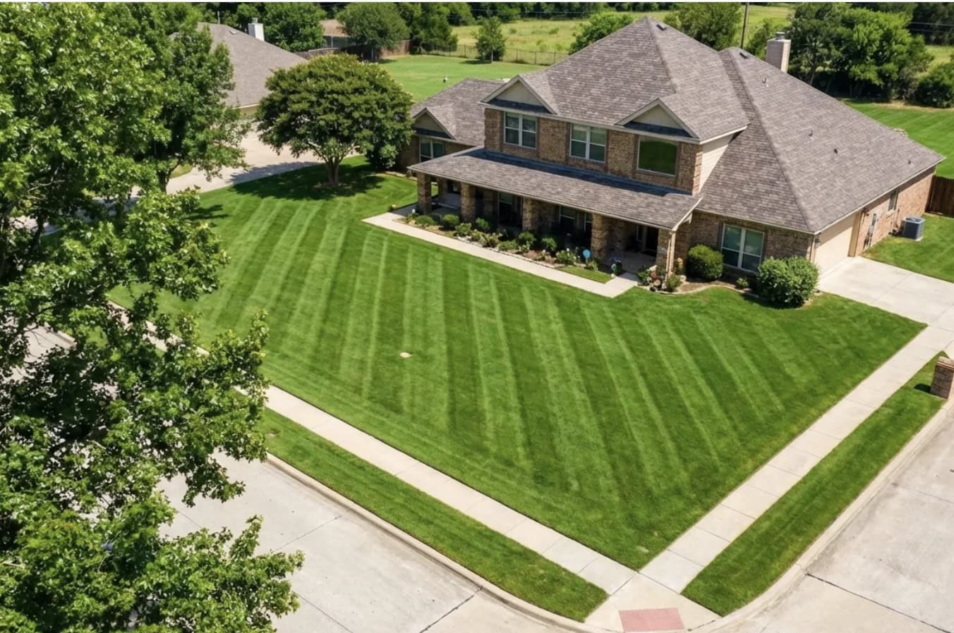 Aerial view of a thick, healthy green lawn at a Rockwall brick home kept vigorous with microbial aeration by Green Lawn Fertilizing